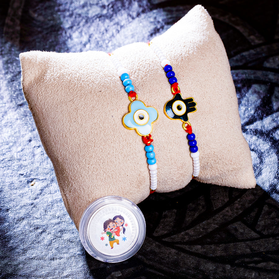 Sukkhi Classy Gold Plated Evil Eye Meenakari Rakhis Set of 2 & 1 Gram 999 Pure Silver Coin Combo with Roli Chawal and Rakhi Greeting Card